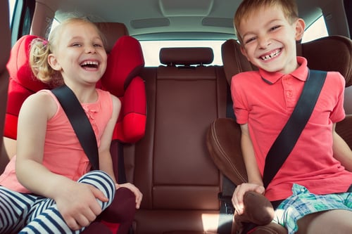 Two kids smiling in the back seat