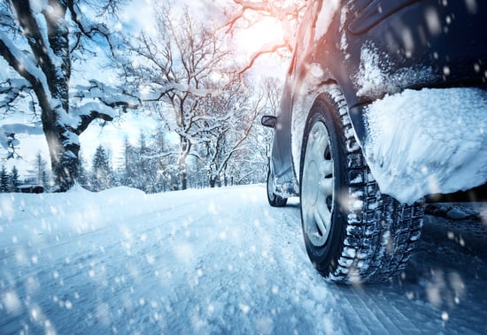 Winter tires on car driving down a snowy road